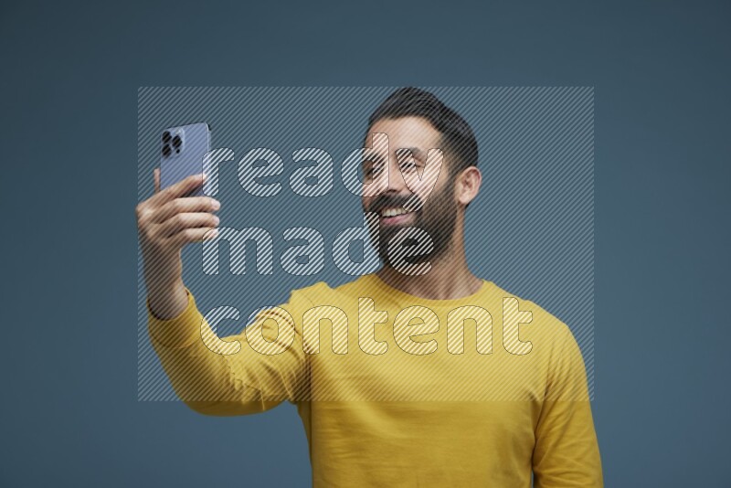 Man Taking a Selfie  in a blue background wearing a yellow shirt