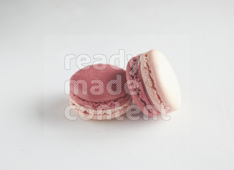 45º Shot of two Pink Litchi Raspberry macarons on white background