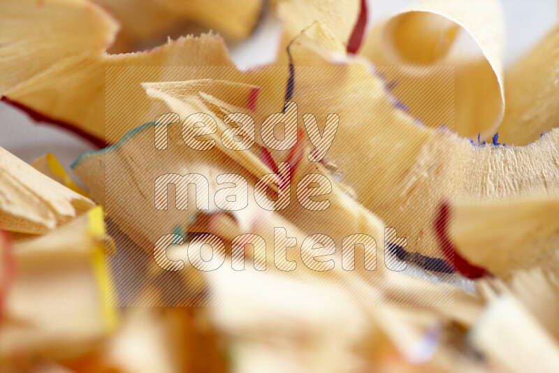 A close-up showing a small pile of pencil shavings with varied color edges on grey background