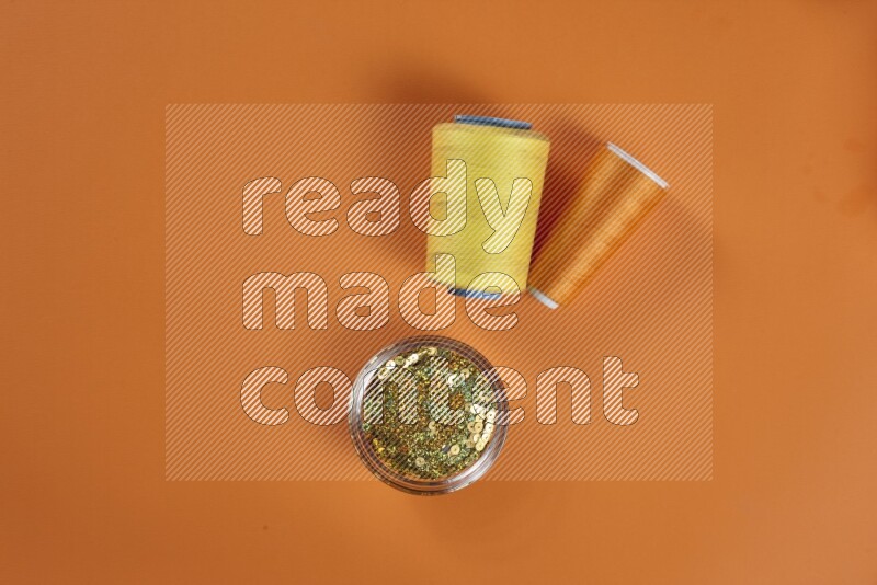 مجموعة من أدوات الخياطة والتفصيل صفراء اللون على خلفية برتقالية