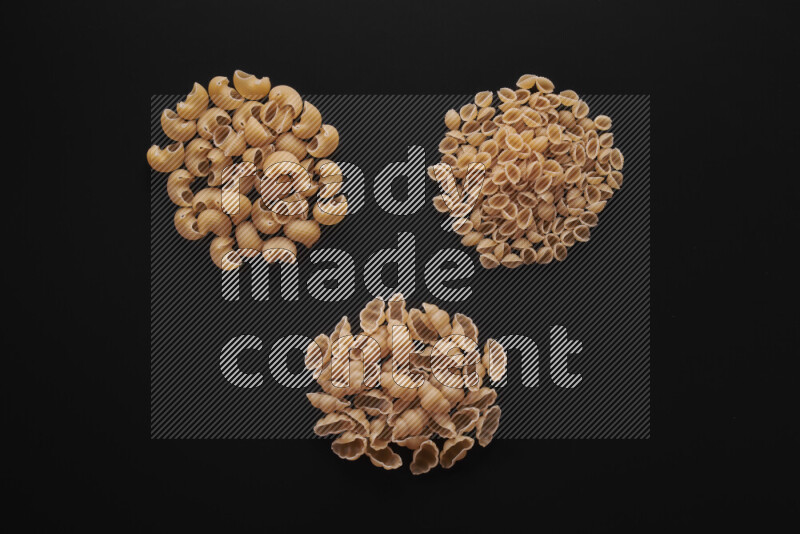 Different pasta types in bunches on black background