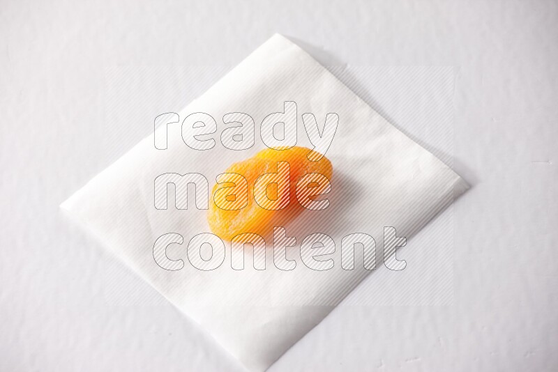 Two dried apricots on a piece of paper on a white background in different angles
