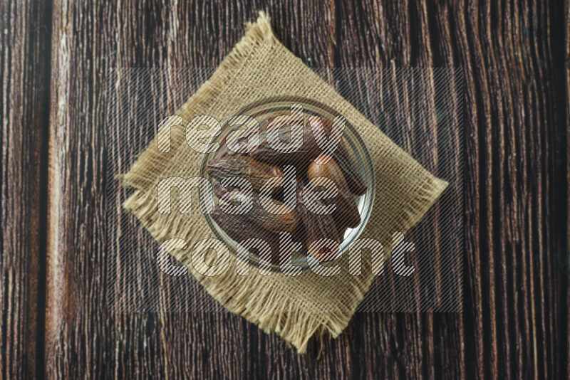 Dates in different bowls (wooden, pottery and glass) on wooden background
