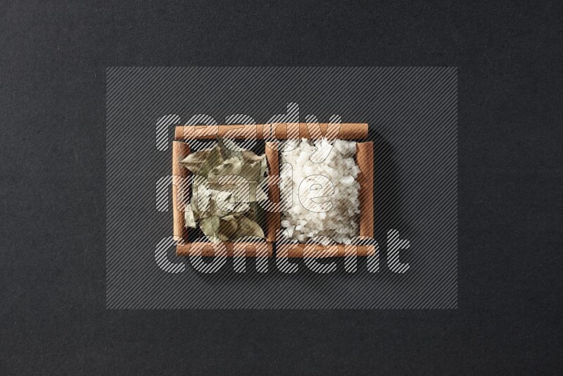 2 squares of cinnamon sticks full of salt and bay laurel on black flooring