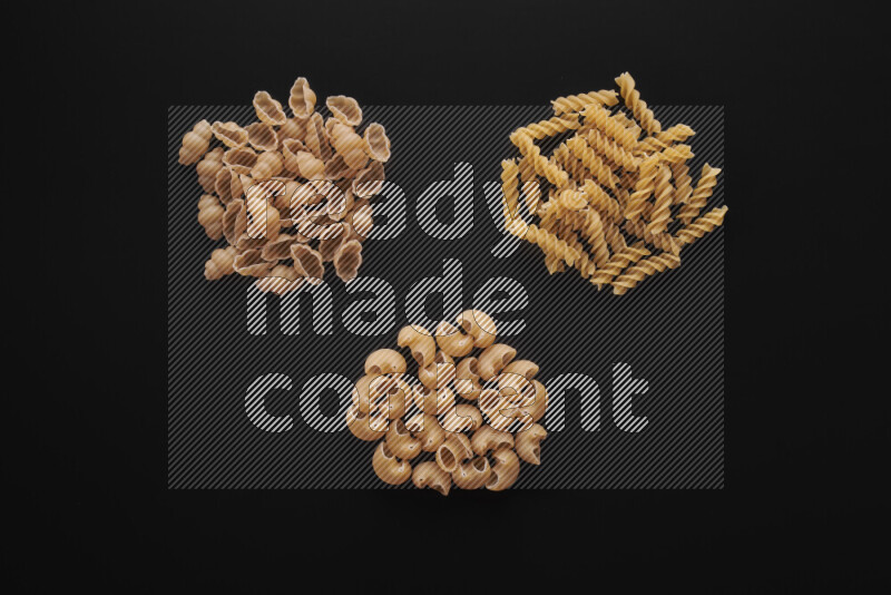 Different pasta types in bunches on black background