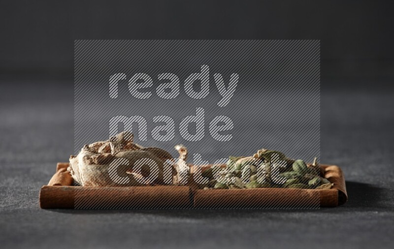 2 squares of cinnamon sticks full of cardamom and dried ginger on black flooring