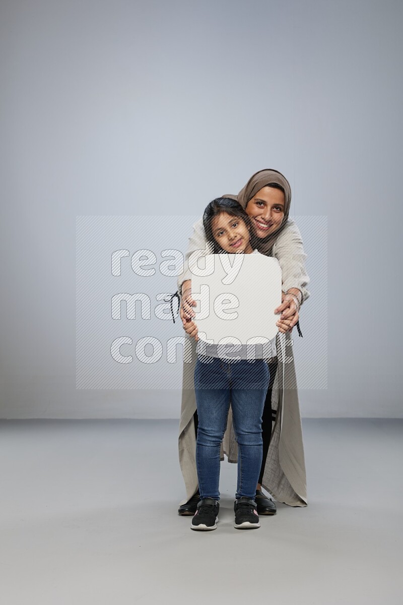 Mom and daughter standing holding social media sign on gray background