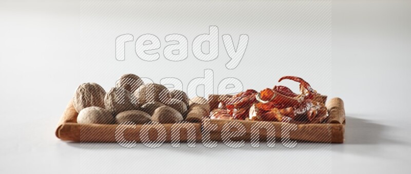 2 squares of cinnamon sticks full of dried red chilis and nutmegs on white flooring