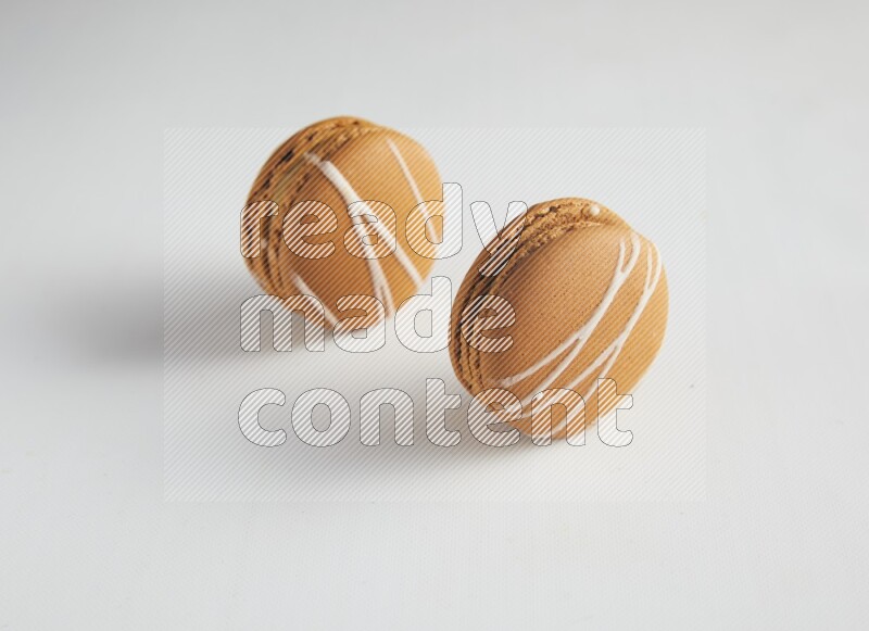 45º Shot of two Brown Irish Cream macarons on white background