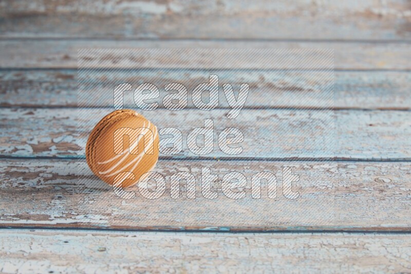45º Shot of Brown Irish Cream macaron on light blue wooden background