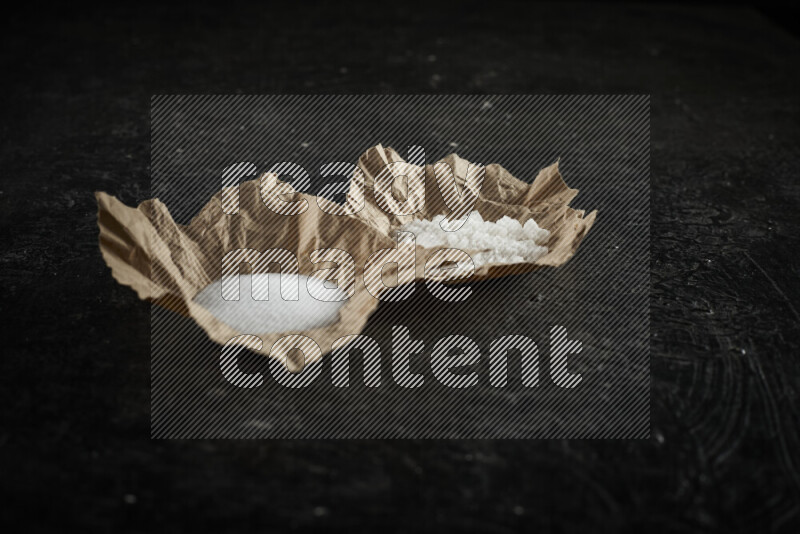 قطعة ورق مجعدة ممتلئة بالملح الأبيض على خلفية سوداء