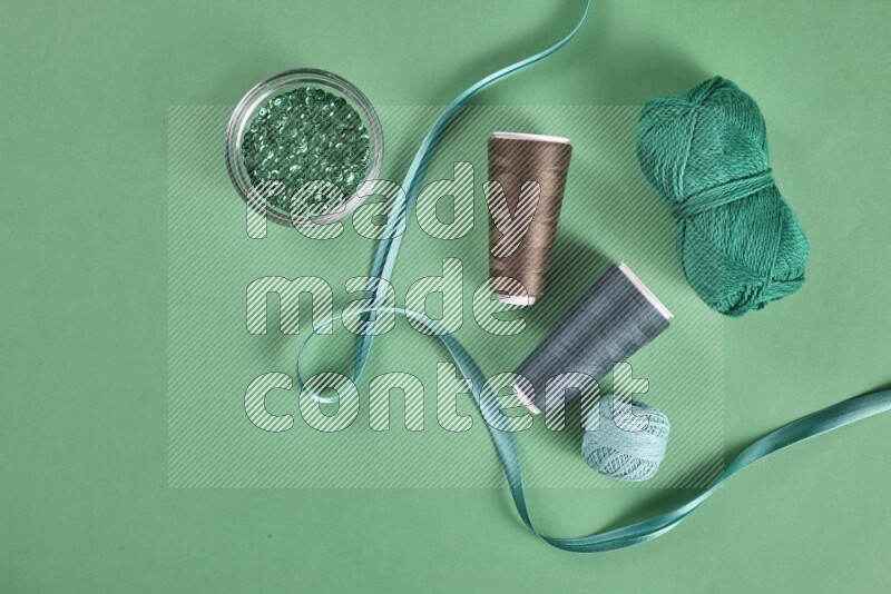 A green collection of sewing and tailoring tools arranged on a green background