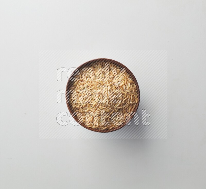 Top-view shot of long grain brown rice in a container on white background