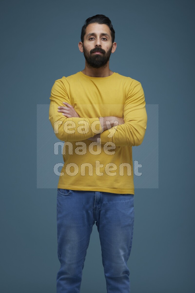 Man posing in a blue background wearing a yellow shirt