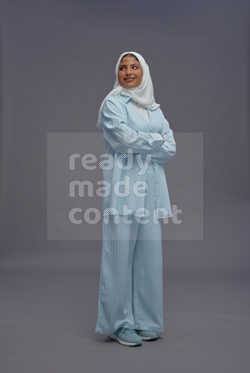 Saudi woman wearing hijab clothes standing with crossed arms on gray background
