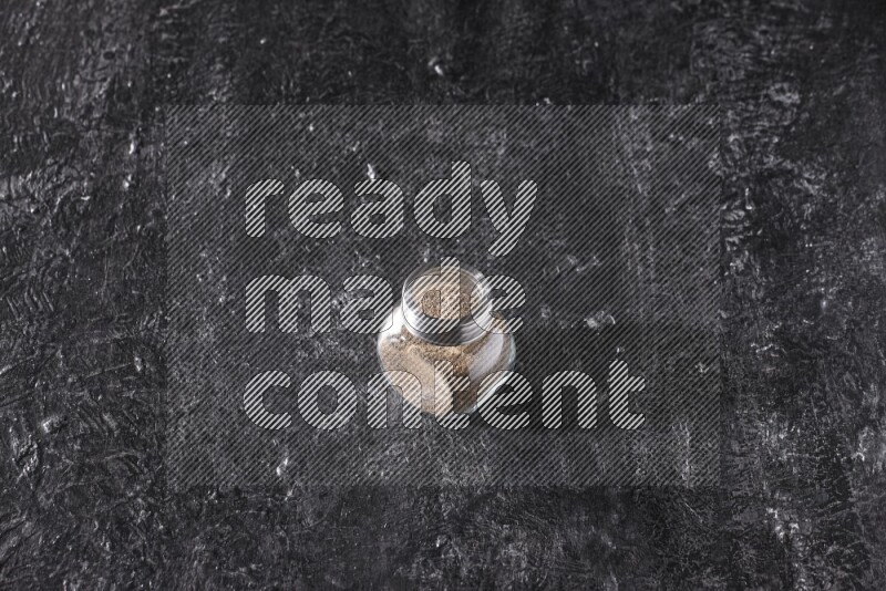 بودرة الفلفل الأسود في وعاء زجاجي علي خلفية سوداء