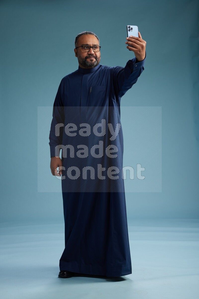 Saudi Man without shimag Standing taking selfie on blue background