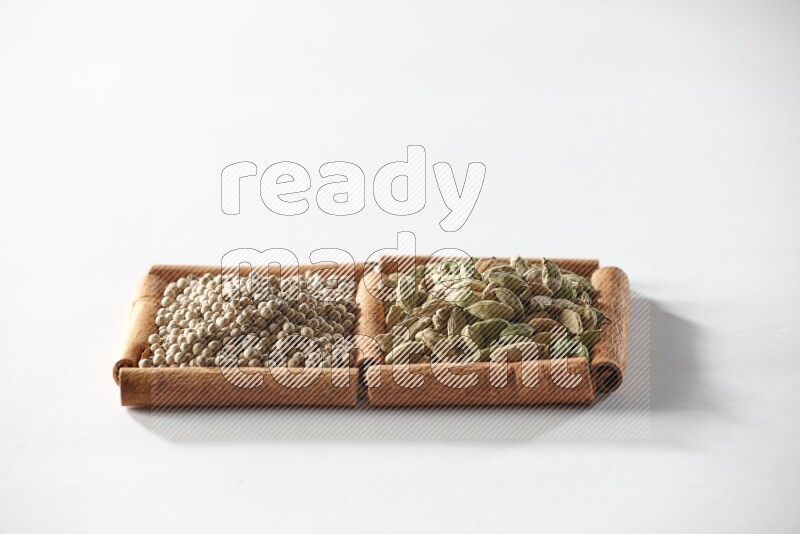 2 squares of cinnamon sticks full of cardamom and white pepper on white flooring