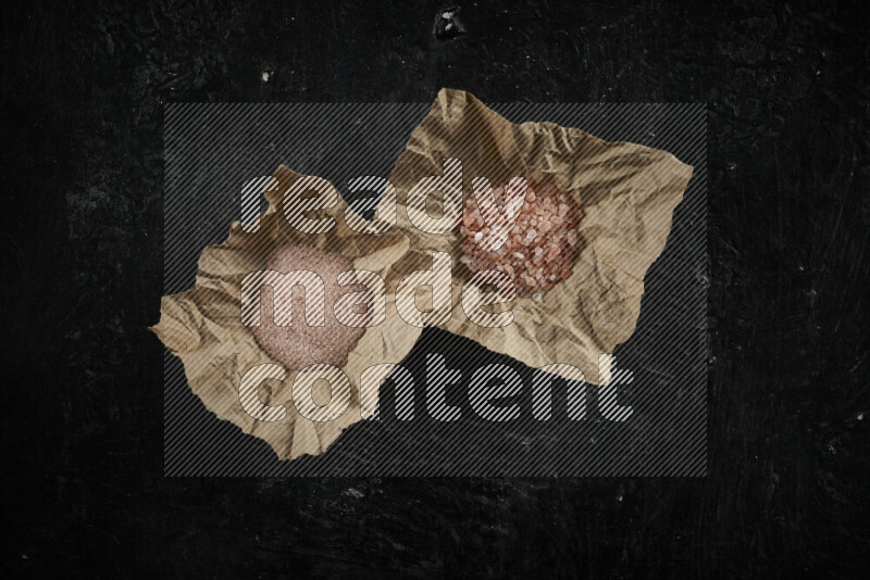 قطعة ورق مجعدة ممتلئة بملح الهيمالايا الوردي على خلفية سوداء