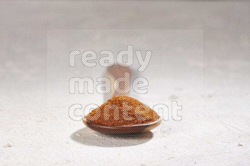 A wooden ladle full of ground paprika powder on white background