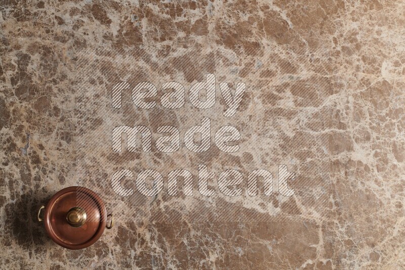 A small copper pot on beige marble background