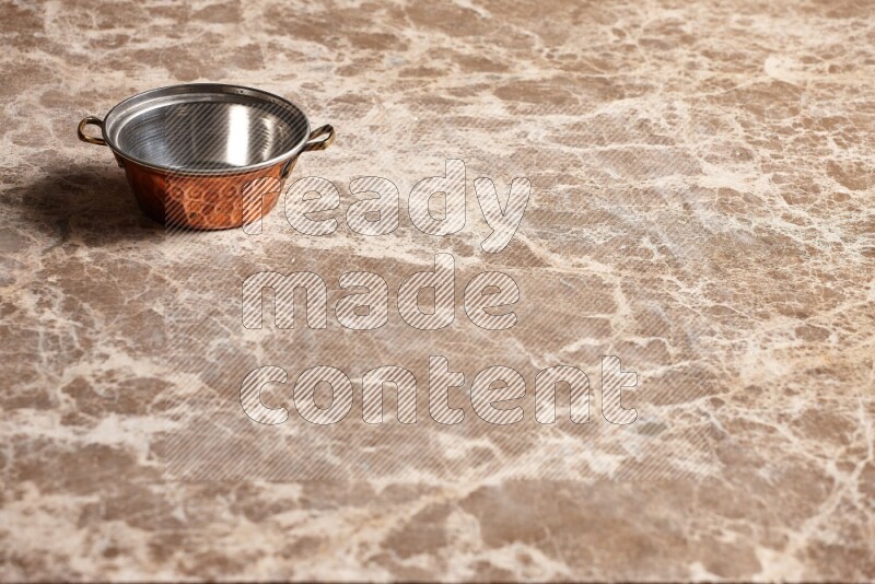 A small copper pot on beige marble background