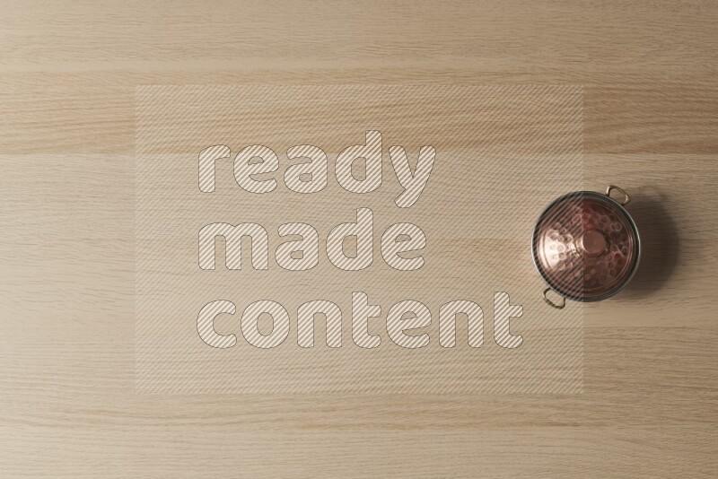 A small copper pot on light wooden background