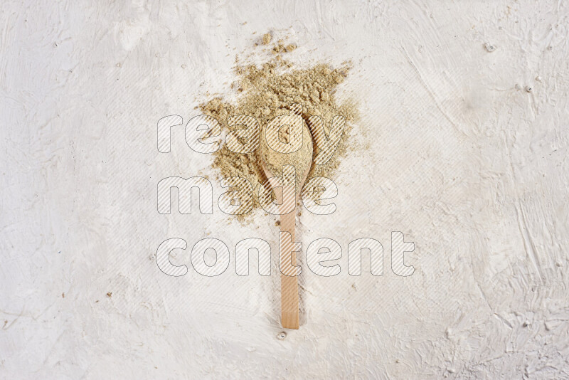 A wooden spoon full of ground ginger powder on white background