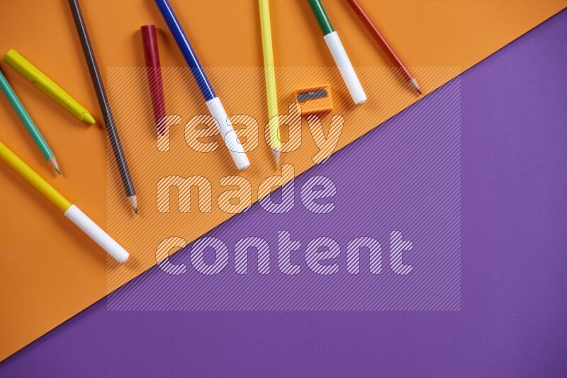 A mix of colored pencils, crayons on orange and purple background
