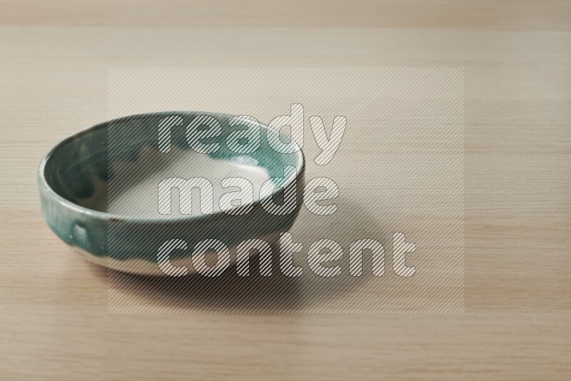 A multicolored pottery bowl on light wooden background