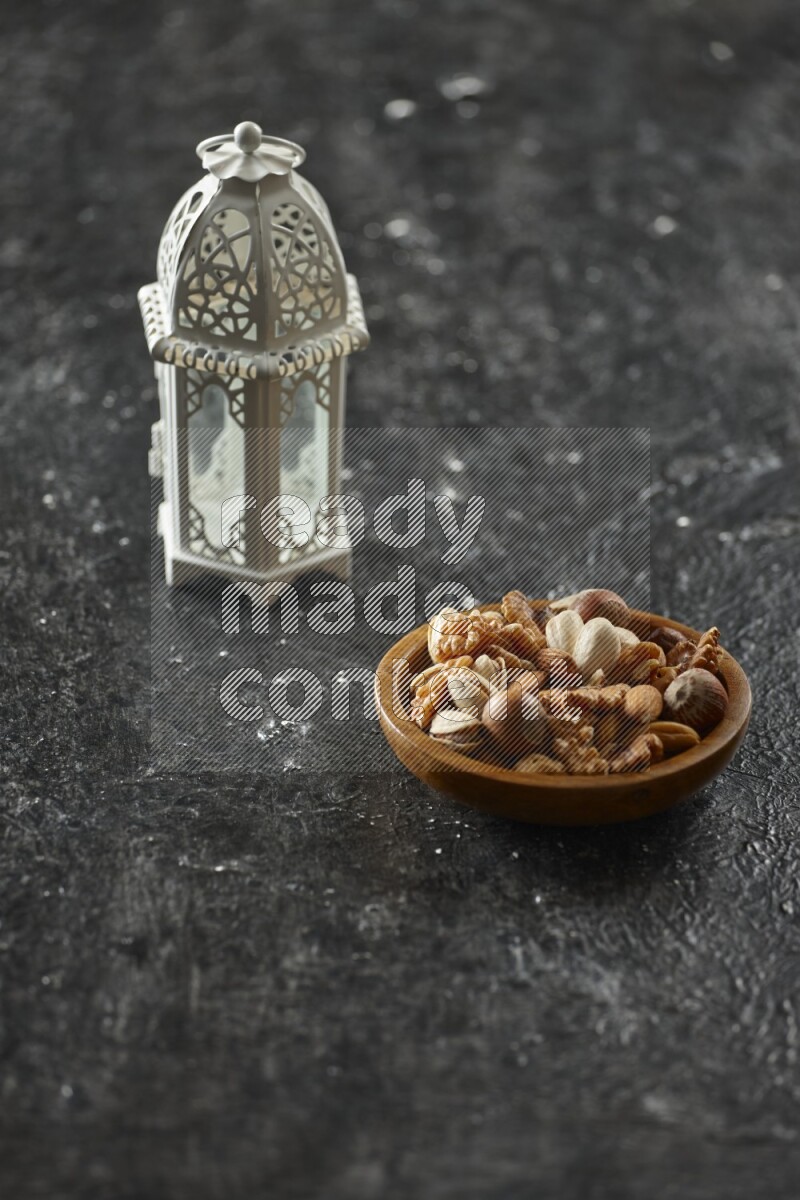 A white lantern with different drinks, dates, nuts, prayer beads and quran on textured black background