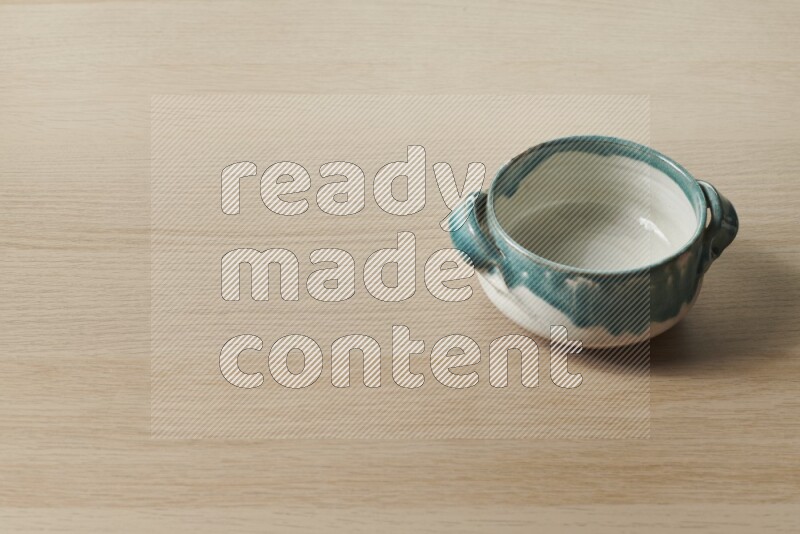 A multicolored pottery bowl on light wooden background