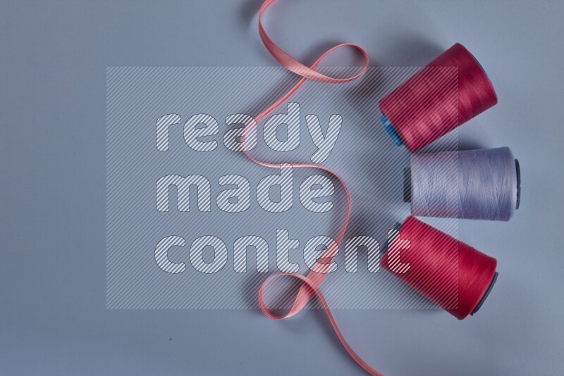 A pink collection of sewing and tailoring tools arranged on a blue background