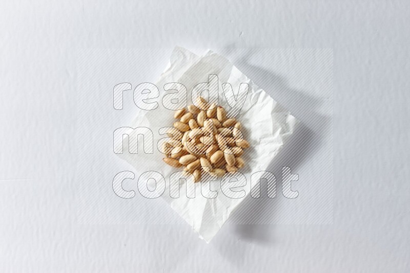 Peeled peanuts on a crumpled piece of paper on a white background in different angles