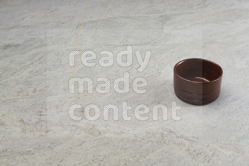 A brown pottery bowl on grey marble background