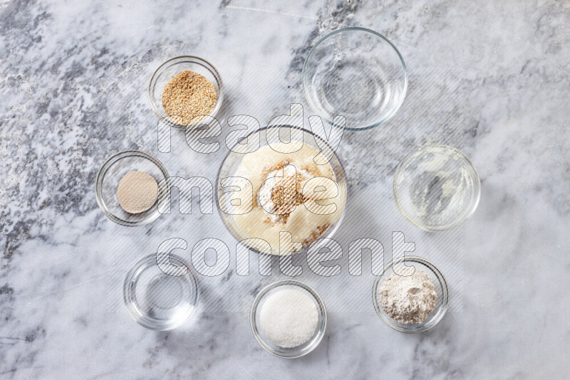 Kahk step by step with its ingredients ghee, sugar, flour, sesame, yeast, water and kahk flavor on grey marble background