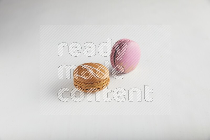 45º Shot of of two assorted Brown Irish Cream, and Purple Strawberry macarons on white background