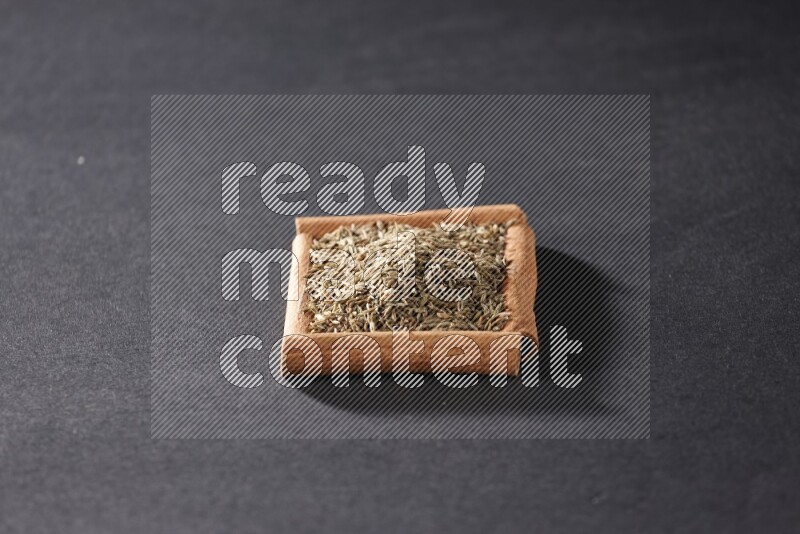 A single square of cinnamon sticks full of cumin on black flooring