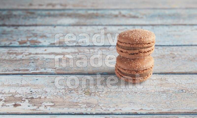 45º Shot of two Brown Hazelnuts macarons on light blue wooden background
