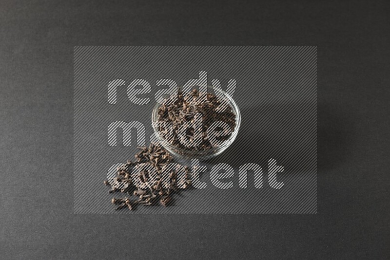 A glass bowl full of cloves on a black flooring