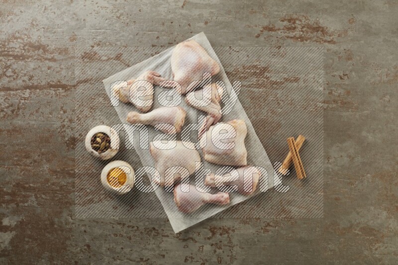 Mixed fresh chicken pieces on a parchment paper direct on a textured rustic background
