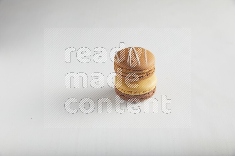45º Shot of of two assorted Brown Irish Cream, and Yellow, and Brown Chai Latte macarons on white background