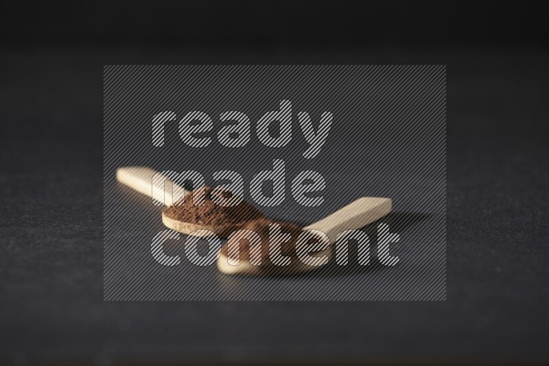 ملعقتان خشبيتان ممتلئتان ببودرة القرنفل على خلفية سوداء