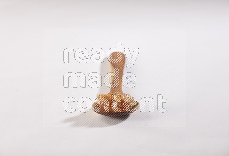 A wooden ladle filled with gum arabic on white flooring