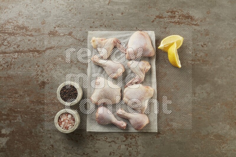 Mixed fresh chicken pieces on a parchment paper direct on a textured rustic background