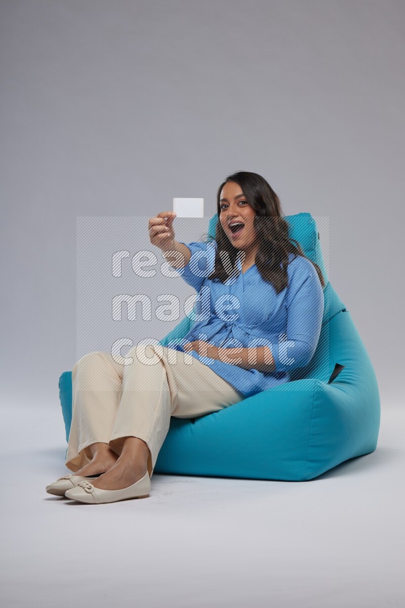 A woman sitting on a blue beanbag and holding ATM card