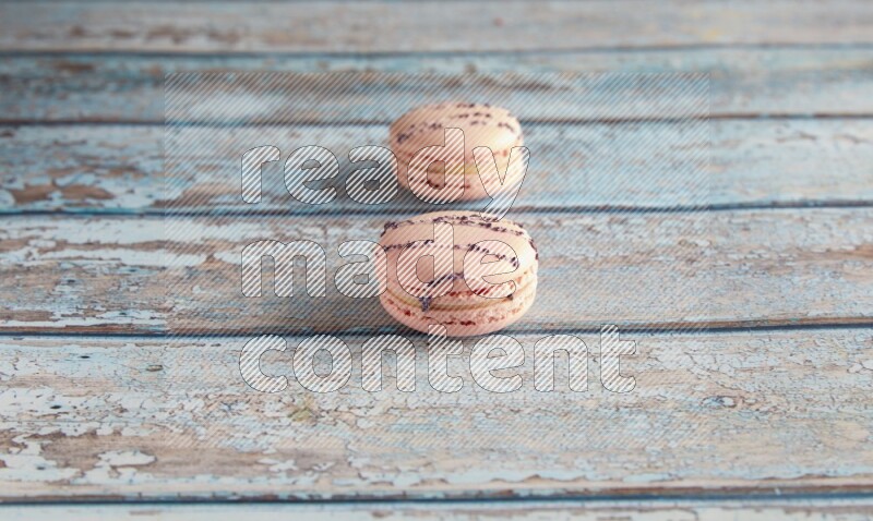 45º Shot of two pink orange blossom macarons on light blue wooden background