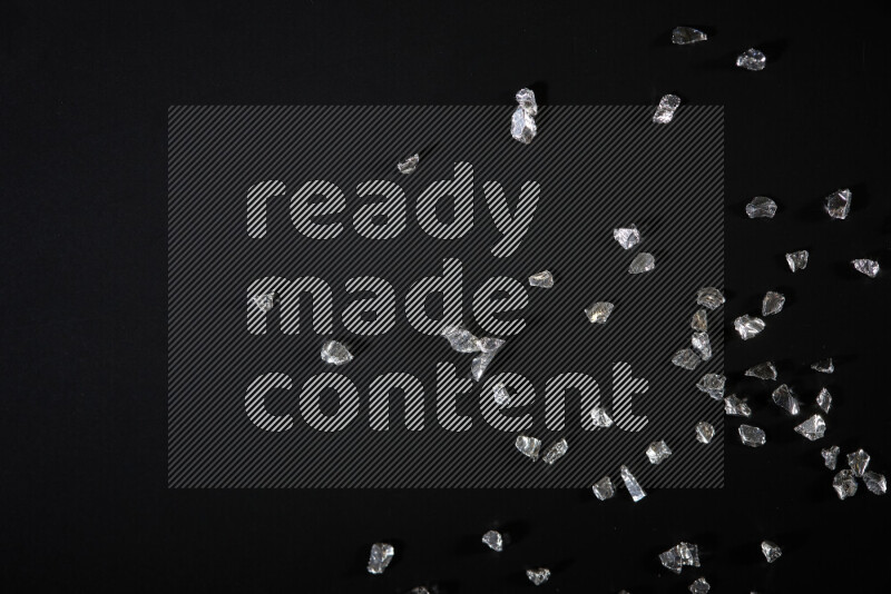 قطع زجاجية فضية لامعة متناثرة على خلفية سوداء