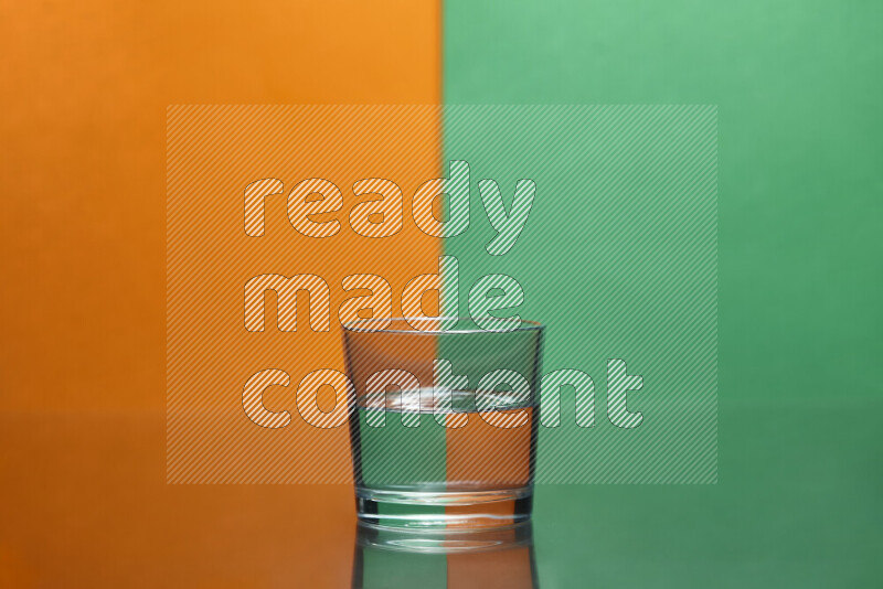 The image features a clear glassware filled with water, set against orange and green background