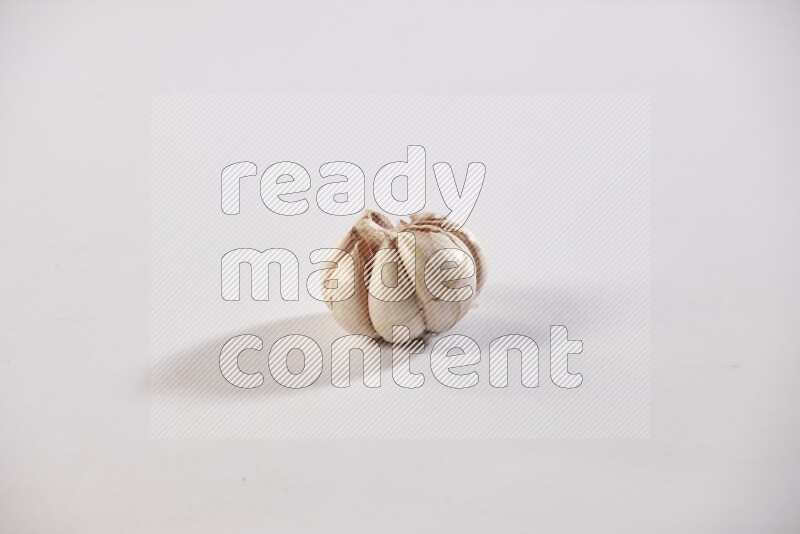 A whole garlic bulb placed on a white flooring